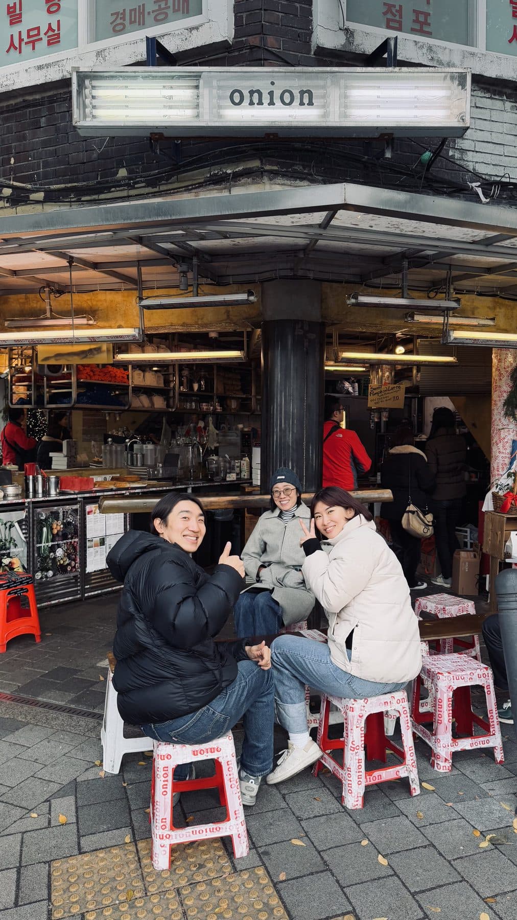 Friends sitting on Onion's branded stools outside the café in Seongsu, Seoul
