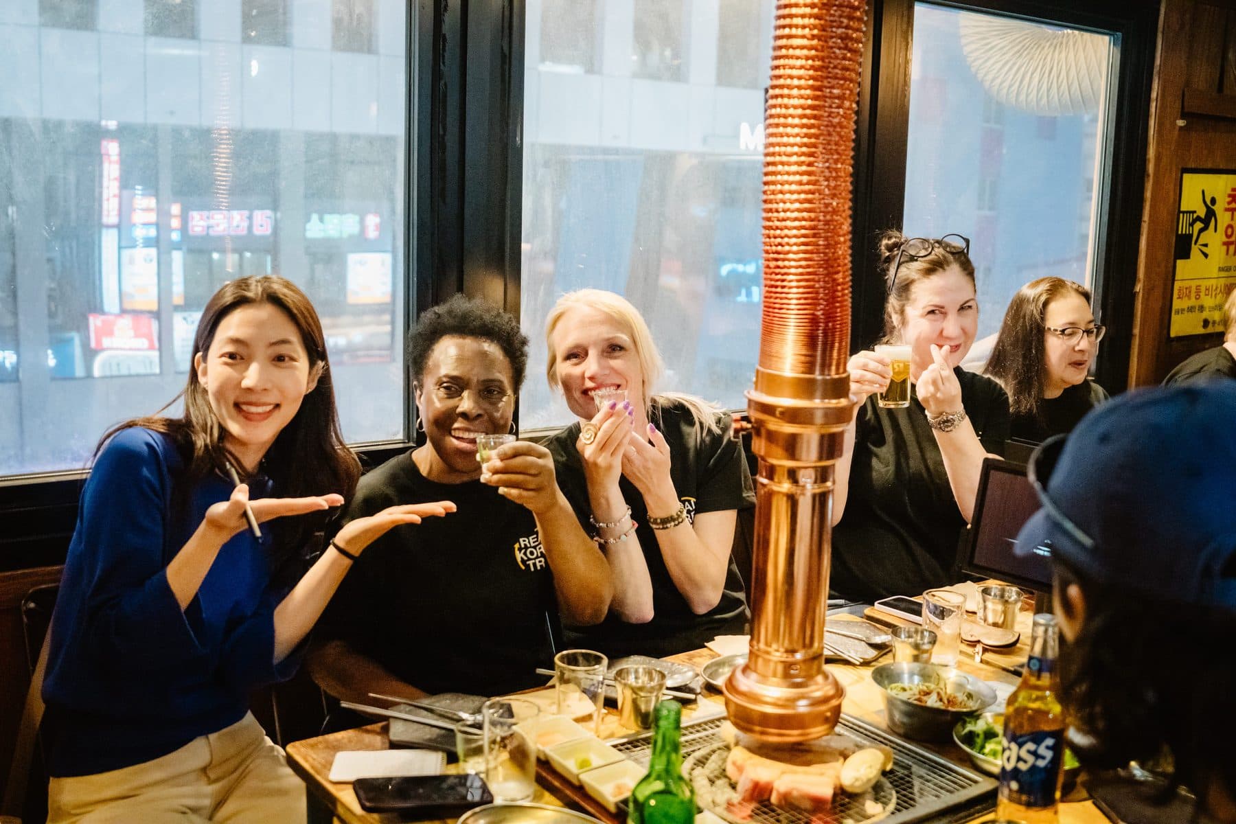 A group sharing a Korean BBQ dinner with soju and grilled pork in Seoul
